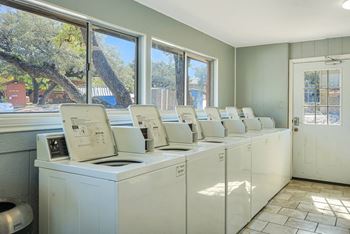 A row of washing machines are lined up in a room.